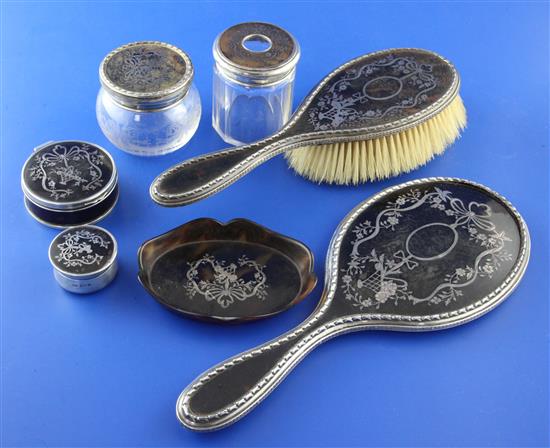 An early 20th century silver and tortoiseshell pique six piece dressing table set, mirror 10.75in.